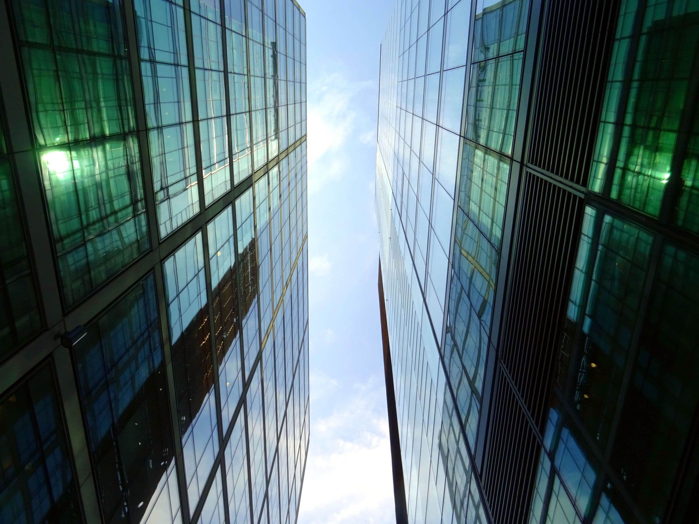 Edifícios corporativos espelhados vistos de baixo, contra o céu.